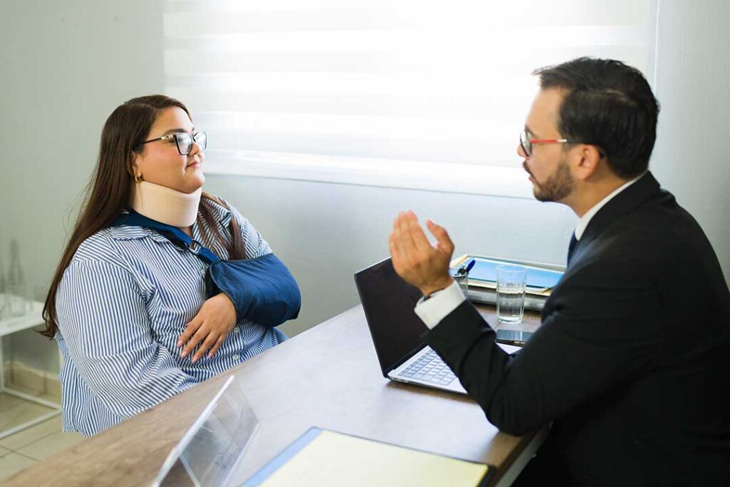 A person reviews a car insurance policy in a home office while medical bills and documents are spread on the table.