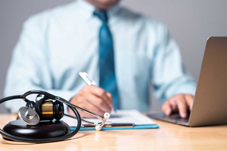 An injured adult reviews medical bills and accident documents at a kitchen table.